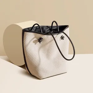 Beige woven bucket bag with black leather trim, casual large capacity shoulder handbag.