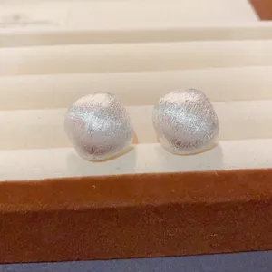 Detaillierte Nahaufnahme minimalistischer, gebürsteter Metall-Ohrringe im Retro-Stil.