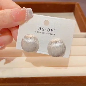 Detailaufnahme minimalistischer silberner Ohrringe mit gebürsteter Metallkugel auf Karte.
