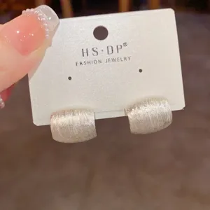 Detailaufnahme trendiger französischer Retro-Ohrringe aus gebürstetem Metall auf Karte.