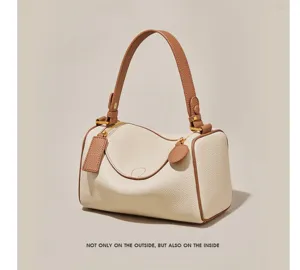 Close-up detail of women's contrast leather pillow bag with brown handle and metal zip.