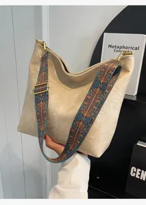 Stijlvolle retro schoudertas detail met brede kleurrijke patroonriem en zacht beige leer.