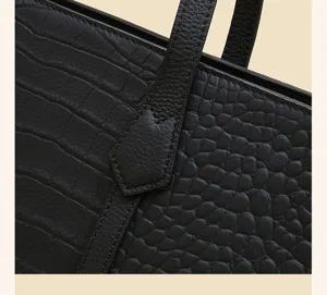 Close-up of black crocodile pattern leather tote bag detail, premium texture and fine stitching.