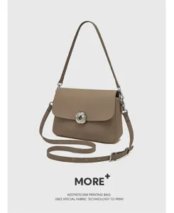 Detailed view of the brown leather shoulder bag featuring unique metal lock and straps.