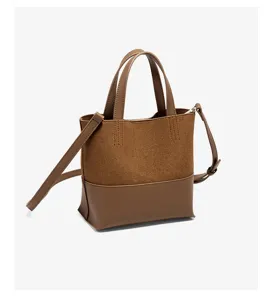 Dettaglio borsa a secchiello in pelle e camoscio marrone con trama di alta qualita e cinghia.