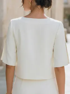 Vista di dettaglio del top corto bianco minimalista da donna con eleganti maniche spaccate.