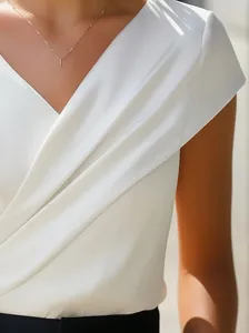 Detalle elegante top blanco manga corta cuello en V con tela drapeada y estilo fino.