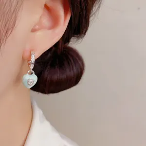 Silver hoop earrings with light green enamel heart pendant, sweet design detail view.