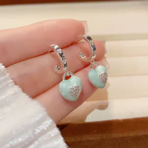 Mint green heart earrings detail shot, silver hoop with sparkling stones close up.