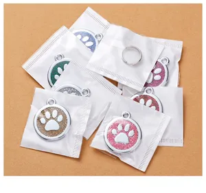Detailed view of round metal pet ID tags with glitter paw print design in individual bags.