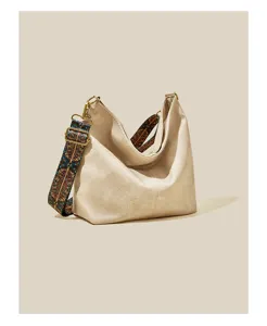 Beige hobo schoudertas voor dames, met brede etnisch geprinte riem en gouden hardware.