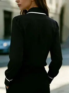Detail view of a chic women's black long sleeve shirt featuring a striking white contrast lapel.