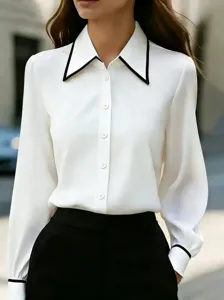 Detail view of a chic white long sleeve blouse featuring a contrast black lapel and button front.