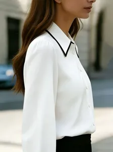 Detail shot of a women's white long-sleeve blouse featuring an elegant black contrast collar.