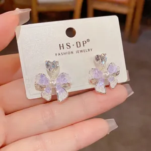 Primer plano de pendientes de lazo de cristal con perlas y pedrería de corazón, vista detallada.