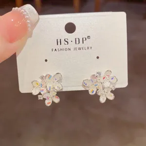 Primer plano de pendientes artesanales de cristal en forma de flor con elementos de color.