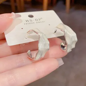 Primo piano di eleganti orecchini a cerchio irregolari con glitter bianchi su cartellino.
