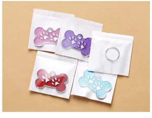 Detailed shot of colorful metal bone pet ID tags with cute paw print design and rings.