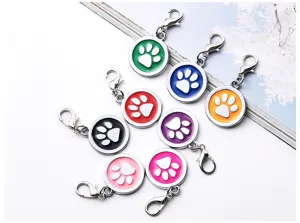 Close-up of colorful round metal pet id tags with cute paw prints and lobster clasps.