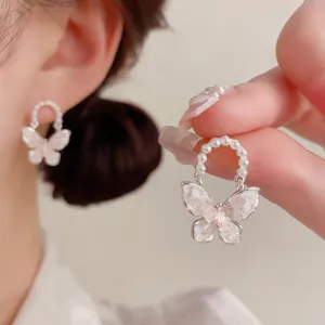 Vista detallada de pendientes de mariposa de cristal hechos a mano con arco de perlas.