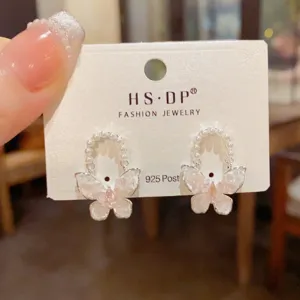 Primer plano detallado de pendientes de mariposa de cristal con aro de perlas, joya fina.