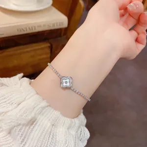 Exquisite rotating shell clover bracelet detail, delicate sparkling rhinestone chain accessory.
