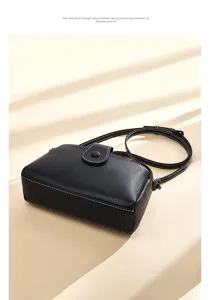 Detailed view of minimalist black leather crossbody bag with elegant white stitching and flap.