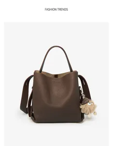 Brown leather bucket bag with cute plush pendant, stylish single shoulder crossbody bag.