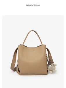 Khaki leather bucket bag detail featuring textured material and cute fluffy hedgehog keychain.