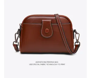 Classic brown leather crossbody bag with contrast white stitching and front pocket detail.