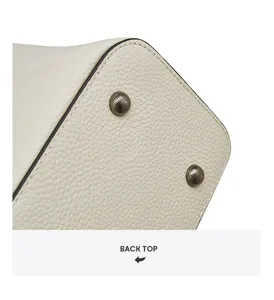 Cream leather tote bag bottom detail showcasing fine texture and durable metal protective feet.