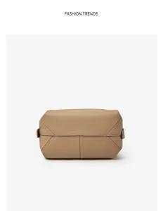 Detail shot of minimalist pebbled leather pouch with geometric folded design and strap.