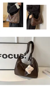 Detailed view of retro brown faux leather hobo shoulder bag with plush charm and wide strap.