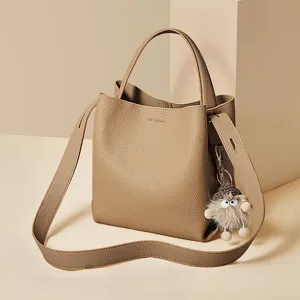 Khaki bucket bag with top handle, wide shoulder strap and cute fluffy plush doll charm.