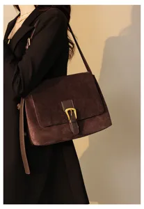 Detailed view of women brown suede shoulder bag, elegant vintage messenger bag with metal buckle.