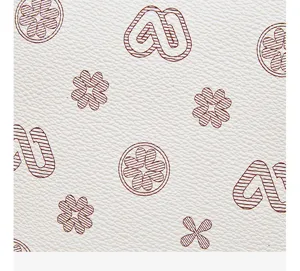 Close-up detail view of white luxury leather with classic brown monogram clover print pattern.