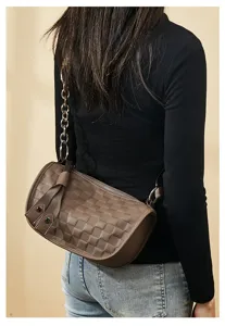 Brown checkered cylindrical shoulder bag on body, detailed view of strap and pattern.