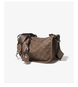 Brown leather shoulder crossbody pillow bag with woven grid texture and wide strap details.