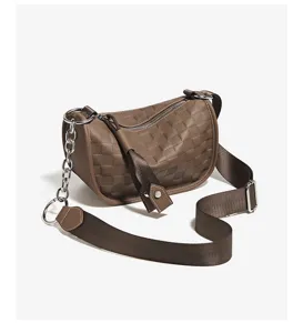 Brown leather pillow shoulder bag detail view showcasing textured surface and metal chain.