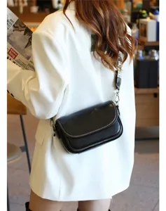 Detailed view of the stylish black leather crossbody bag featuring a wide woven strap.
