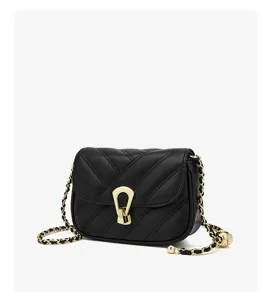 Close-up detail of black quilted crossbody bag with gold chain strap and unique metal lock clasp.