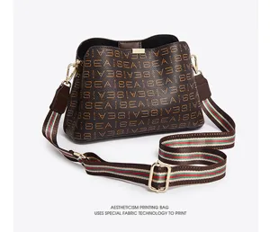Brown bucket shoulder bag with monogram print and striped webbing strap for women daily use.
