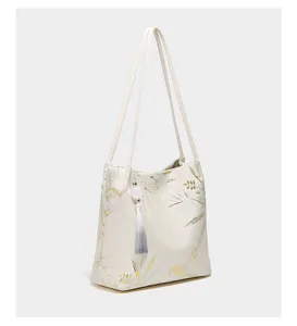 Detailed view of elegant Chinese style tote handbag featuring bamboo print and tassel pendant.