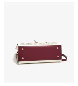 Detailed bottom view of the two-tone structured handbag with metal feet and elegant embroidery.