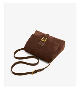 Close-up detail of brown suede women's crossbody bag with elegant golden hardware buckle