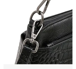 Black leather handbag detail showing metal hardware and crocodile embossed texture.