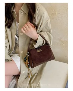 Detalle del bolso de hombro retro de ante con asa trenzada y herrajes metálicos finos.