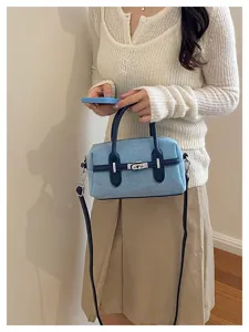 Stylish denim bowling shoulder bag with contrast handles, metal lock, chic crossbody purse.