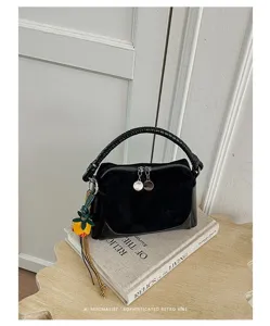 Vista detallada del bolso de mano retro de ante negro con asa tejida y encantador colgante.