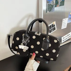 Close-up detail of the chic black and white polka dot handbag, featuring dual handles & charm.